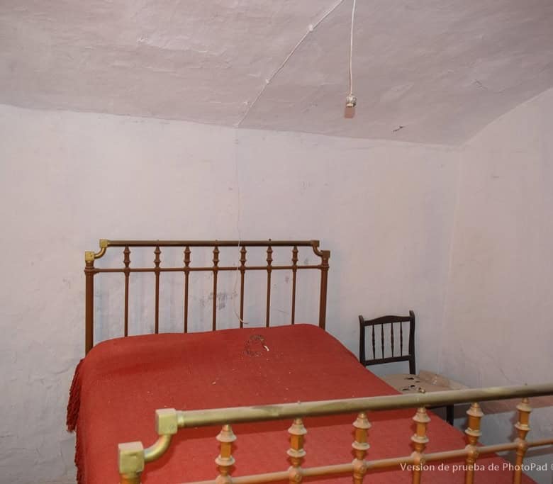 Cave house interior in Cullar, Granada with rustic bed and simple furnishings.