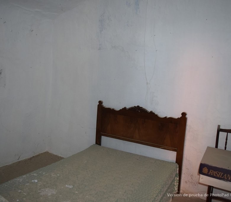 Cave house interior in Cullar, Granada, showcasing rustic walls and vintage furniture.
