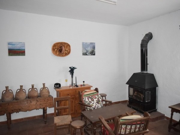 Charming interior of a farm property in Baza, Granada featuring rustic furniture and a wood-burning.