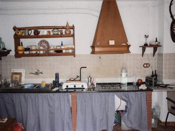 Charming farm property kitchen in Baza, Granada with rustic decor, wooden shelves, and essential app.