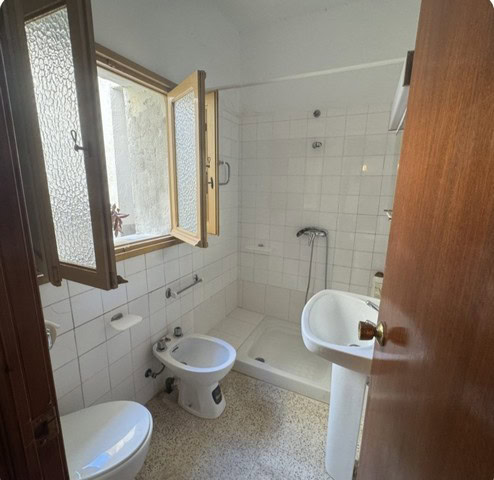 Bathroom in a town house in Purchena, Almeria, featuring a shower, toilet, and sink with natural lig.