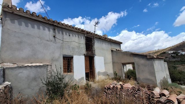 Rural property in Albox, Almeria, featuring a rustic house with tiled roof and scenic mountain views.