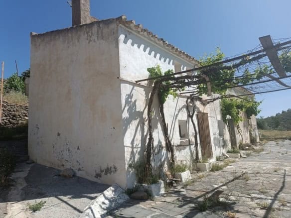 Rural property in Caniles, Granada featuring a traditional whitewashed exterior and lush greenery. P.