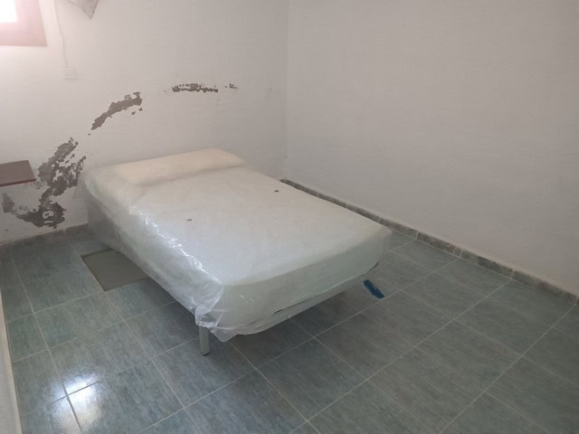 Affordable rural property in Caniles, Granada, featuring a simple bedroom with basic furnishings. Id.