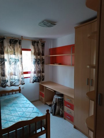 Charming apartment in Seron, Almeria, featuring a simple bedroom with a bed, desk, and storage. Idea.