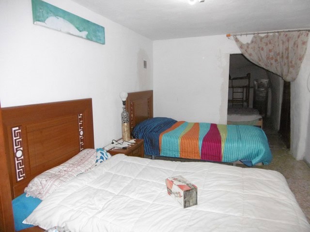 Cave house interior in El Margen, Granada with two beds and rustic decor.
