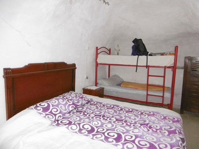 Charming cave house interior in El Margen, Granada, featuring a double bed and bunk beds, ideal for.