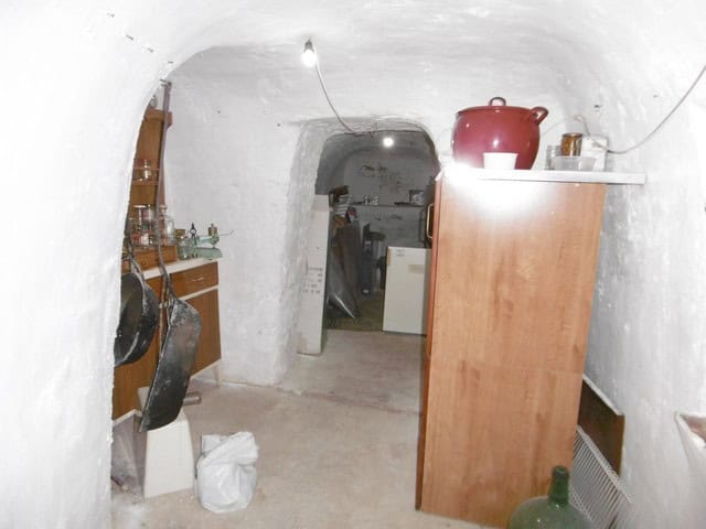 Cave house interior with rustic furniture and storage in El Margen, Granada. Unique underground home.