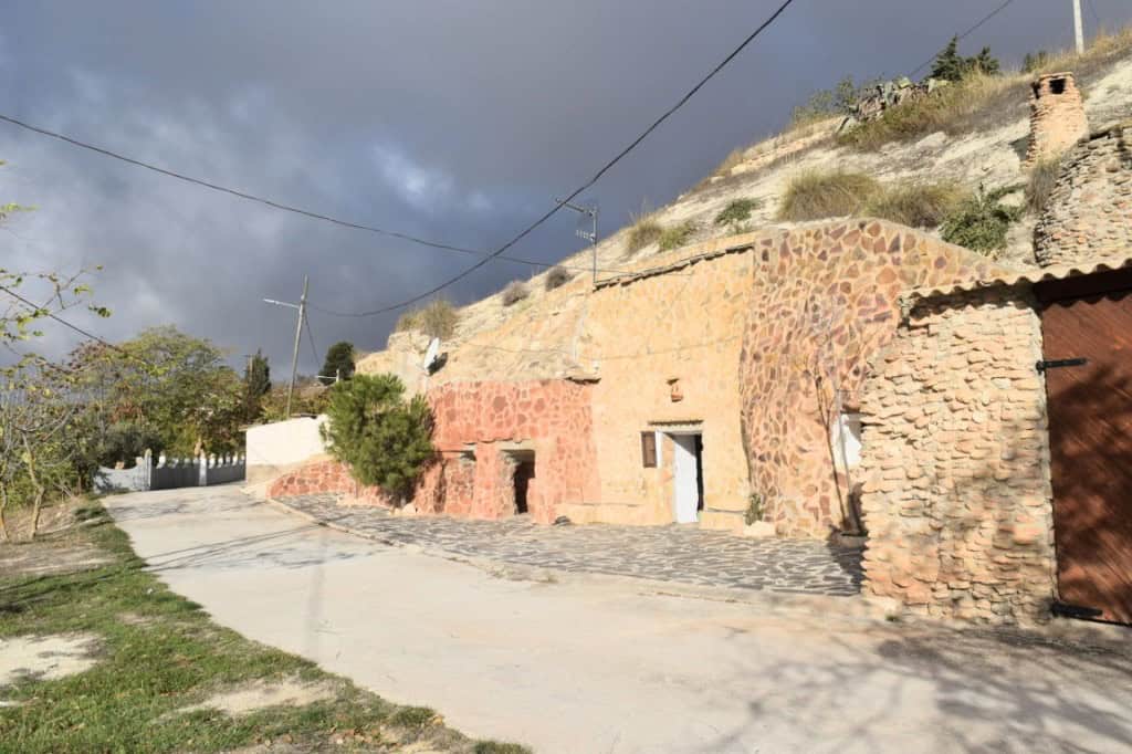 Cave house in Carramaiza, Granada, featuring rustic stone walls and scenic mountain views.