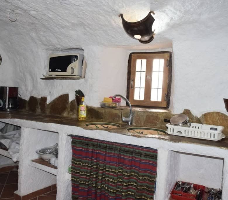 Cave house kitchen with rustic stone walls, small window, and traditional decor in Carramaiza, Grana.
