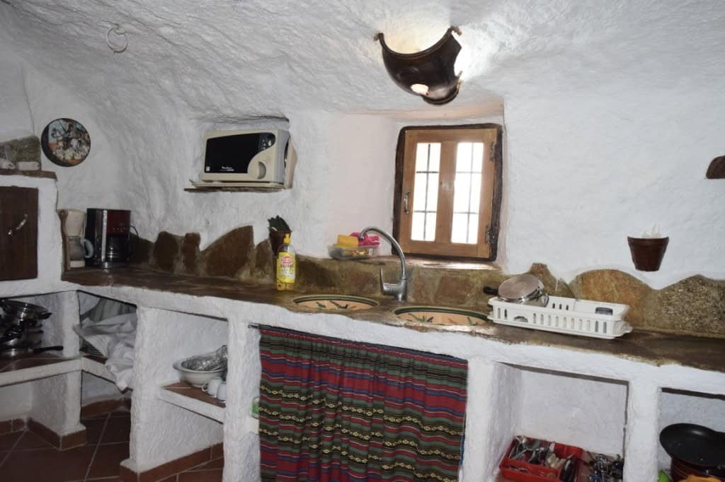 Cave house kitchen with rustic stone walls, small window, and traditional decor in Carramaiza, Grana.