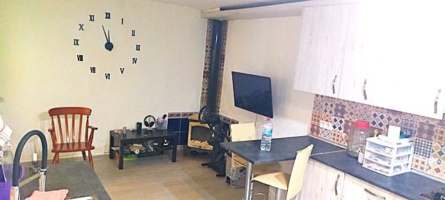 Bright town house living room with wall clock, TV, and kitchen area in Purchena, Almeria.