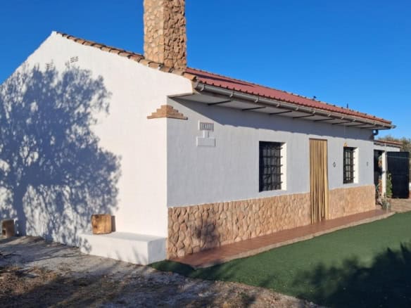 Traditional rural house in Freila, Granada with white walls, stone accents, and a tiled roof, set in.