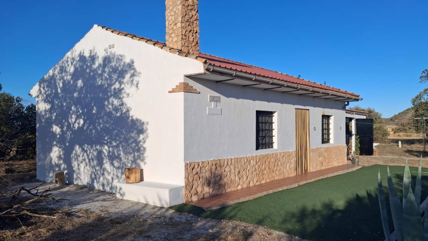 Traditional rural house in Freila, Granada with white walls, stone accents, and a tiled roof, set in.