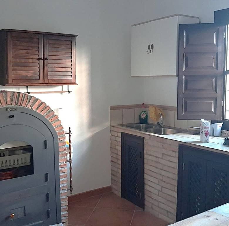 Charming rural home kitchen with traditional oven and wooden cabinets in Freila, Granada.