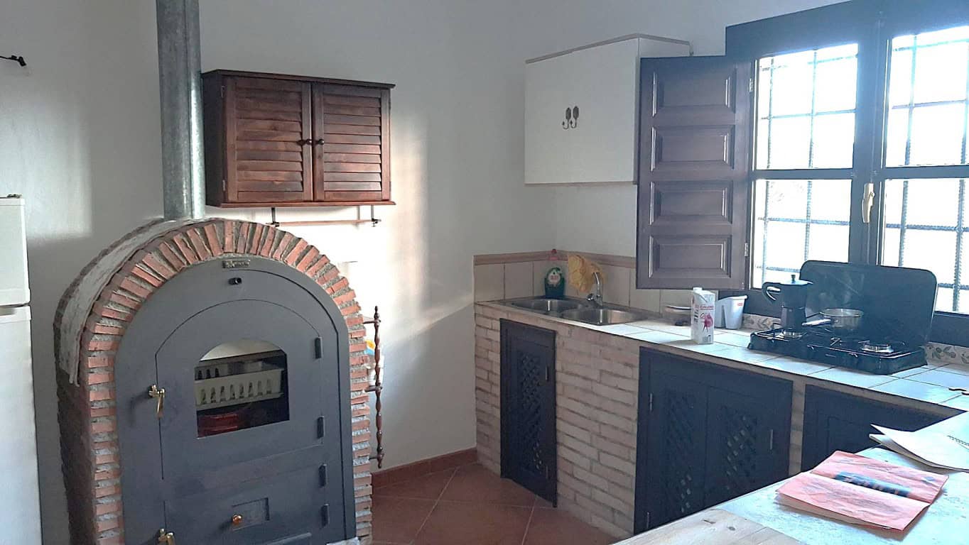 Charming rural home kitchen with traditional oven and wooden cabinets in Freila, Granada.