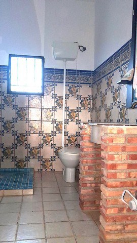 Bathroom with traditional tiles and brick accents in rural Freila, Granada.
