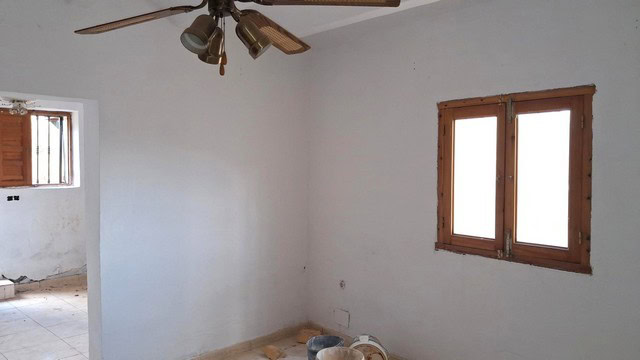 Interior view of a rural property in Albox, Almeria, showing simple white walls and wooden window fr.