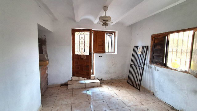 Interior view of a rustic rural property in Albox, Almeria with white walls and wooden window shutte.