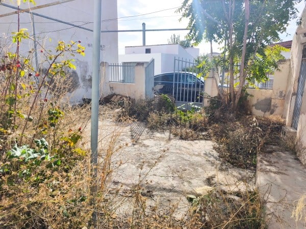 Cave house in Baza, Granada with rustic exterior and surrounding dry vegetation.