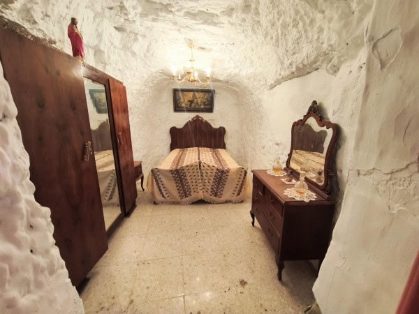 Charming cave house interior in Baza, Granada, featuring rustic furniture and cozy ambiance.