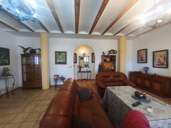 Spacious living room with leather sofas, wooden furniture, and decorative artwork in a rural propert.
