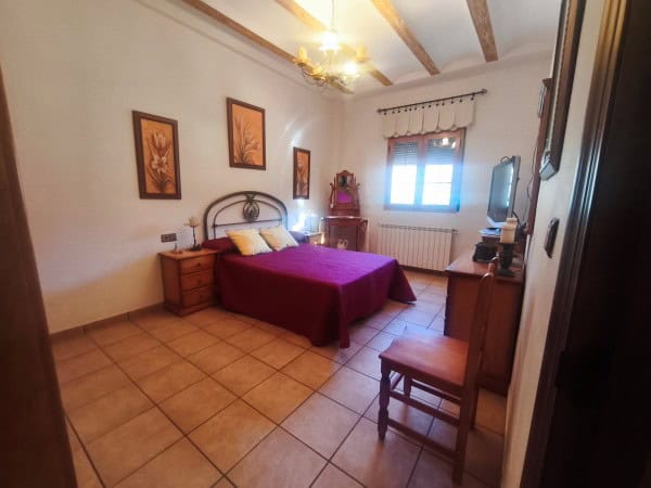 Comfortable bedroom with a double bed, wooden furniture, and natural light in Quesada, Jaen.