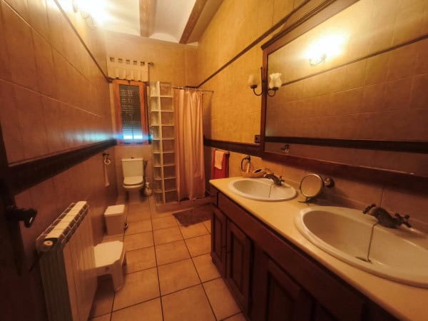 Spacious bathroom with dual sinks, wooden accents, and warm lighting in a rural property in Quesada,.