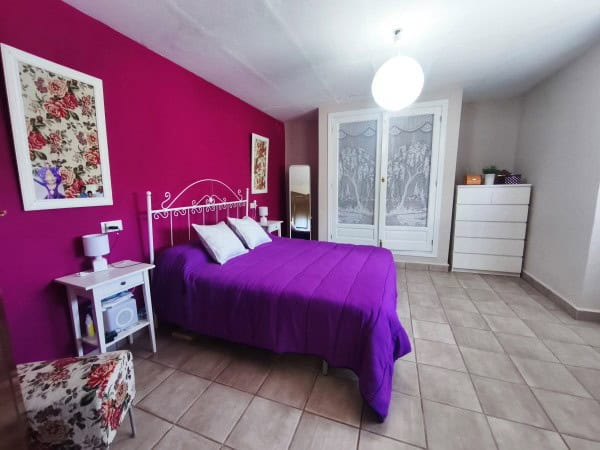 Charming bedroom in rural Quesada, Jaen with vibrant pink wall and cozy furnishings.