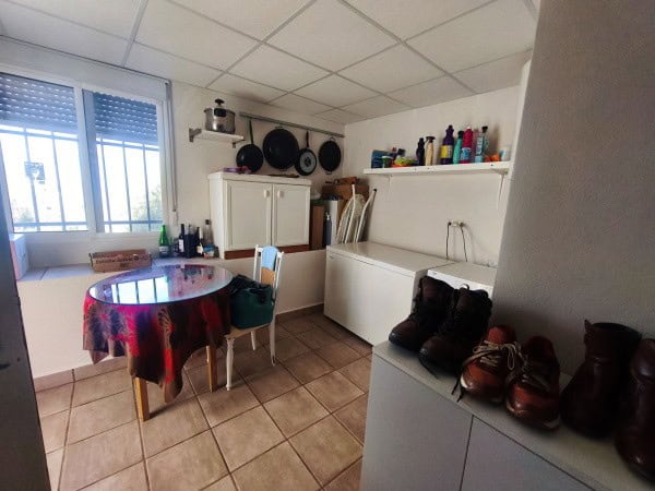 Rural property kitchen with a small dining area, white cabinets, and shelves with kitchenware in Que.