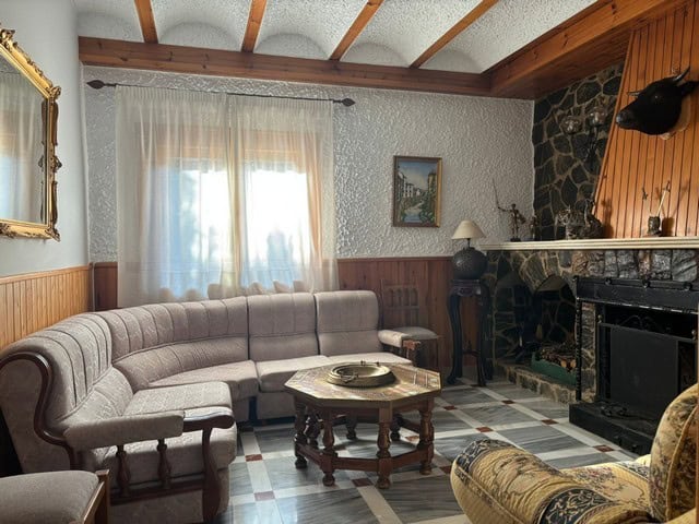 Charming living room in a villa in Cullar, Granada with cozy seating and a traditional fireplace.
