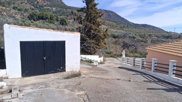 View of a garage and road in Urracal, Almeria, with mountains in the background.