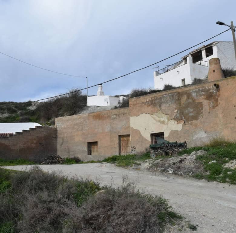 Cave house in Benamaurel, Granada, with whitewashed exterior and rustic features, set on a hillside.