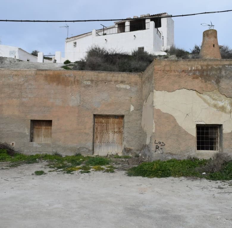 Abandoned cave house in Benamaurel, Granada with weathered walls and small windows.
