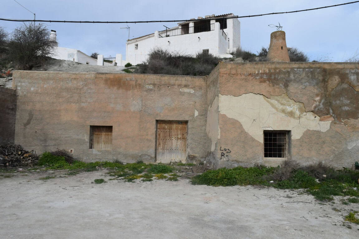 Abandoned cave house in Benamaurel, Granada with weathered walls and small windows.