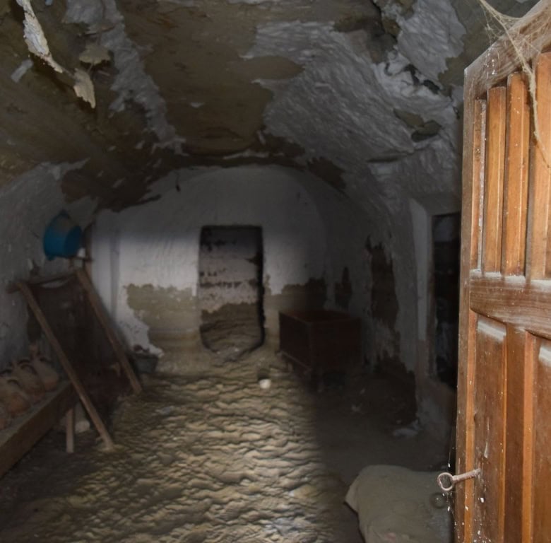 Historic cave house interior in Benamaurel, Granada, showcasing rustic stone walls and wooden door.