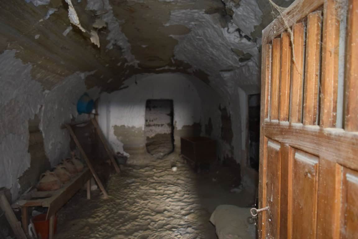 Historic cave house interior in Benamaurel, Granada, showcasing rustic stone walls and wooden door.