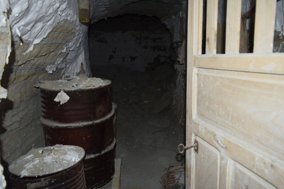 Cave house entrance in Benamaurel, Granada, with barrels and wooden door.