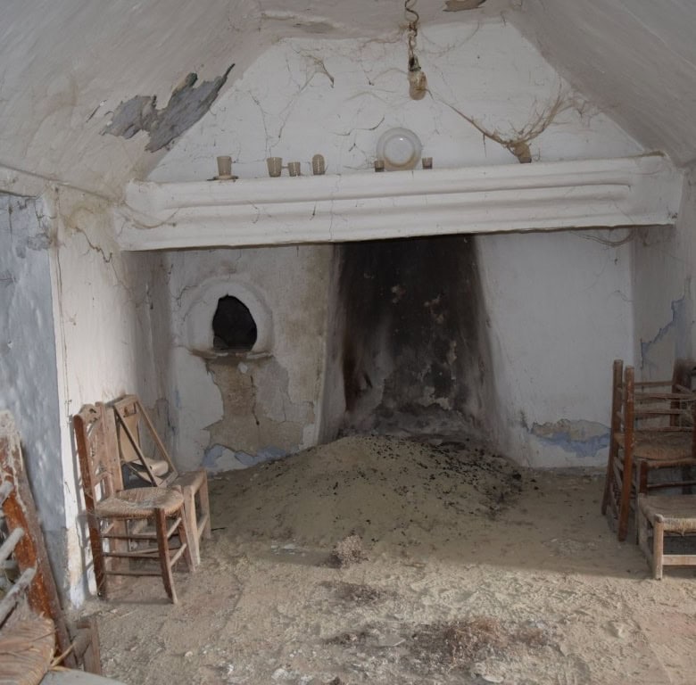 Unique cave house interior in Benamaurel, Granada, featuring rustic wooden chairs and a traditional.