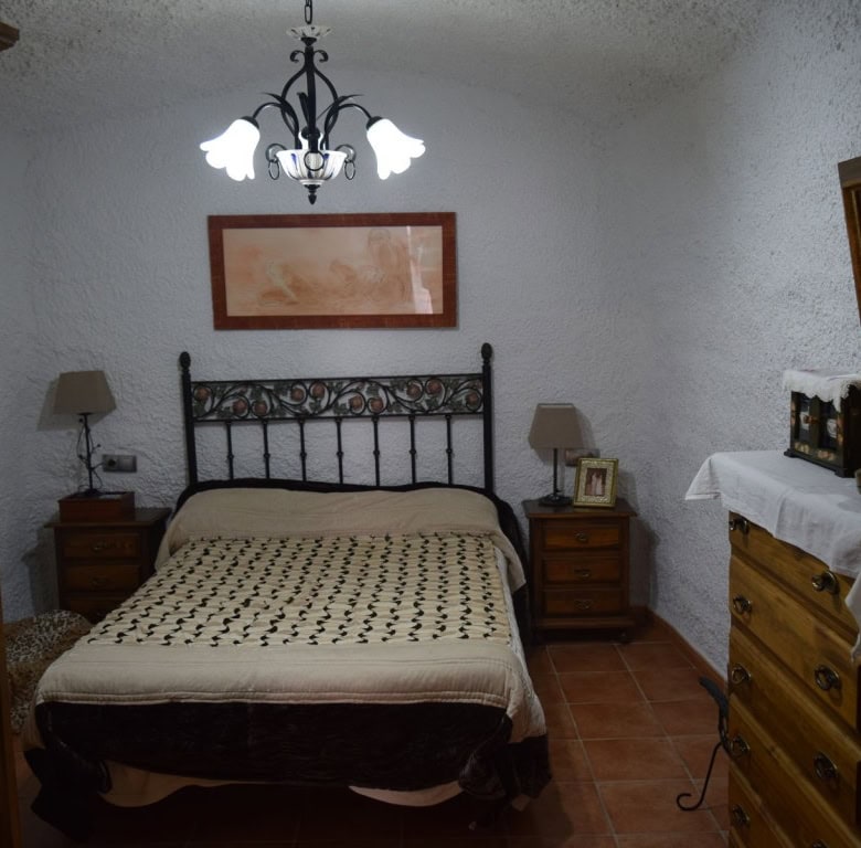 Cozy cave house interior in Freila, Granada, featuring rustic furniture and traditional decor.