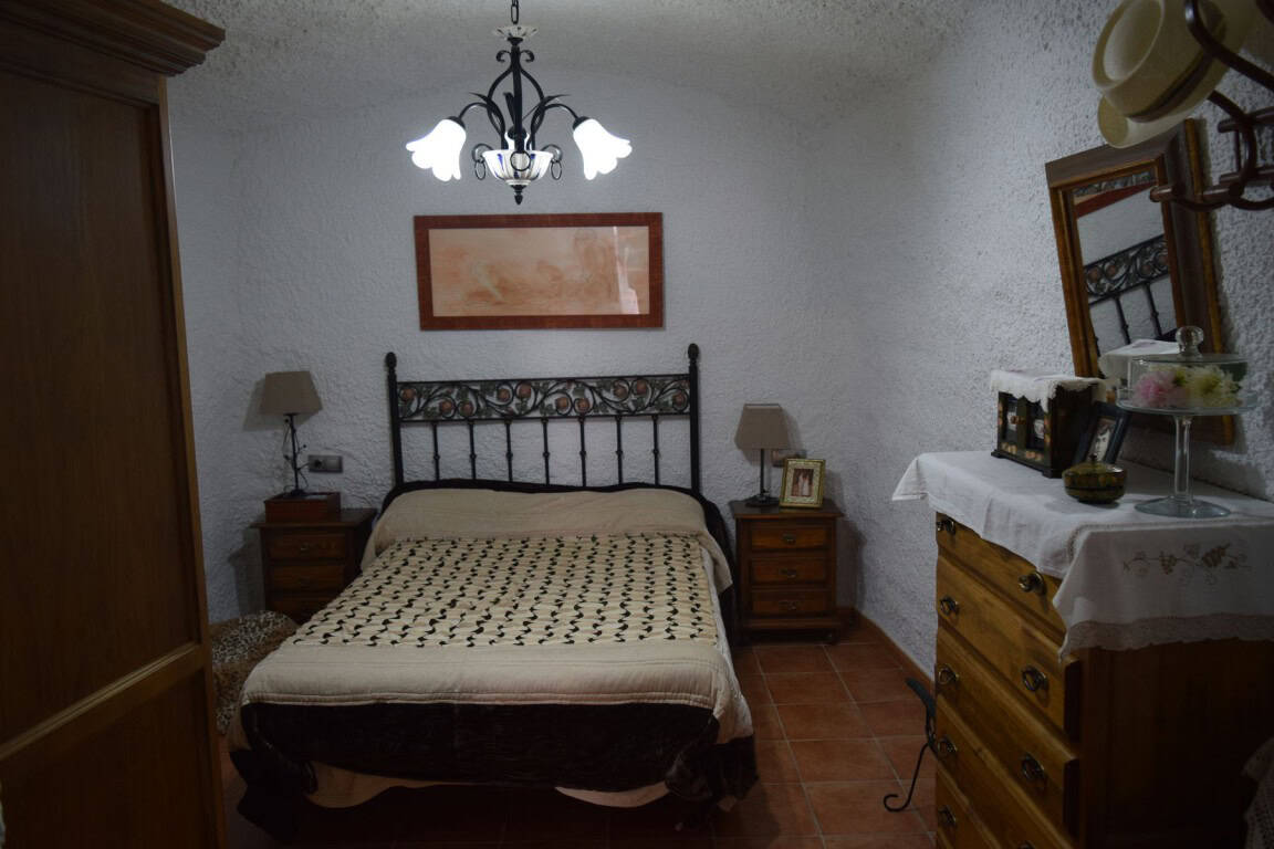 Cozy cave house interior in Freila, Granada, featuring rustic furniture and traditional decor.