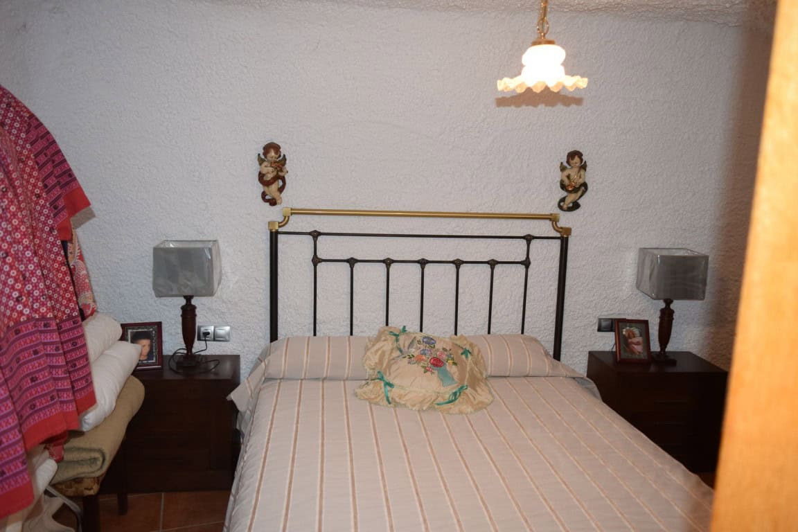 Cave house interior in Freila, Granada, featuring a cozy bedroom with vintage decor.