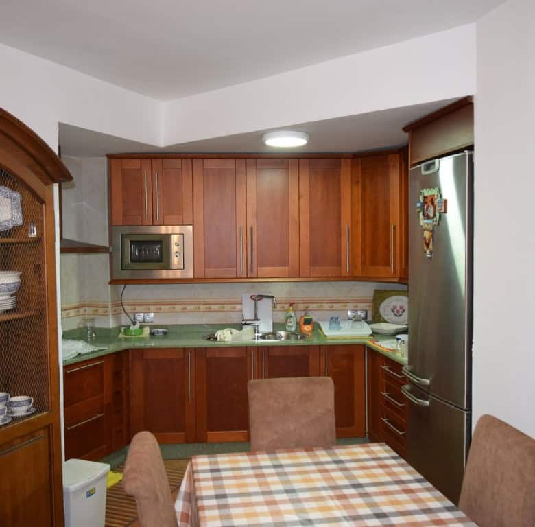 Charming cave house interior in Freila, Granada, featuring wooden kitchen cabinets and cozy dining a.