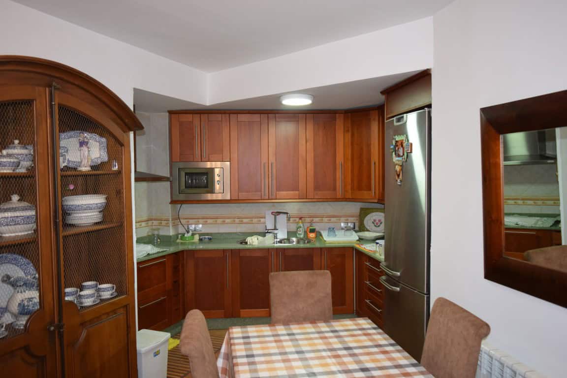 Charming cave house interior in Freila, Granada, featuring wooden kitchen cabinets and cozy dining a.