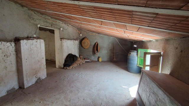 Interior view of a rustic town house in Seron, Almeria, with unfinished walls and storage barrels.