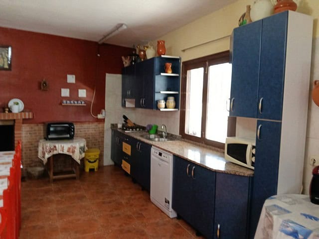 Country home kitchen with traditional decor in Benamaurel, Granada, featuring blue cabinets and rust.