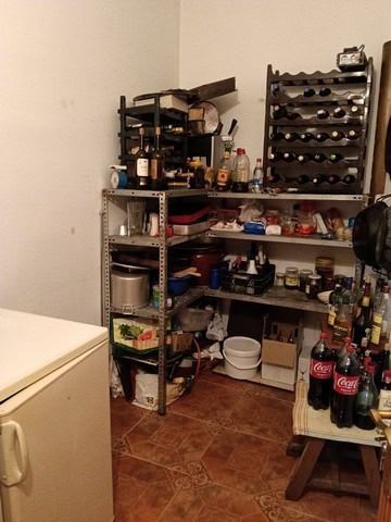 Rustic kitchen with shelves holding bottles, jars, and kitchen essentials in Benamaurel, Granada.