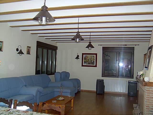 Spacious living room in a finca located in Huescar, Granada, featuring wooden ceiling beams and mode.