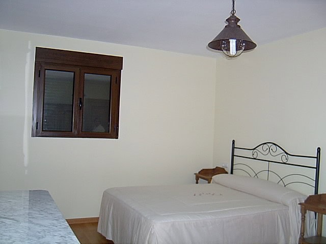 Interior bedroom of a rural finca in Huescar, Granada with simple furnishings and a window.