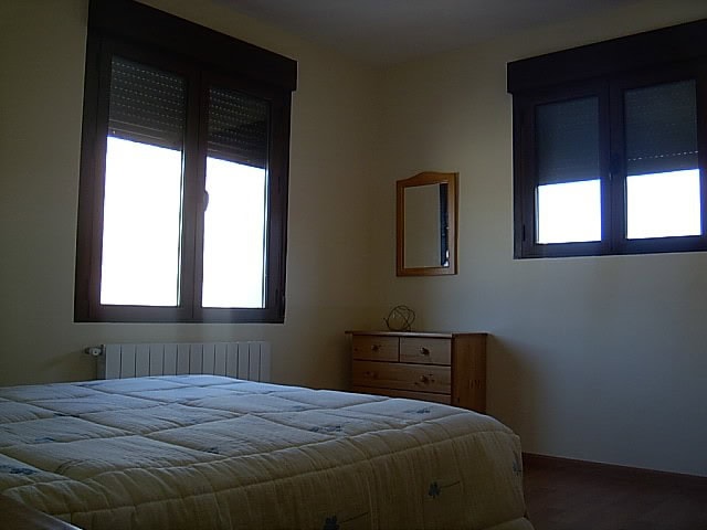 Charming bedroom in a traditional finca located in Huescar, Granada, featuring two windows with natu.